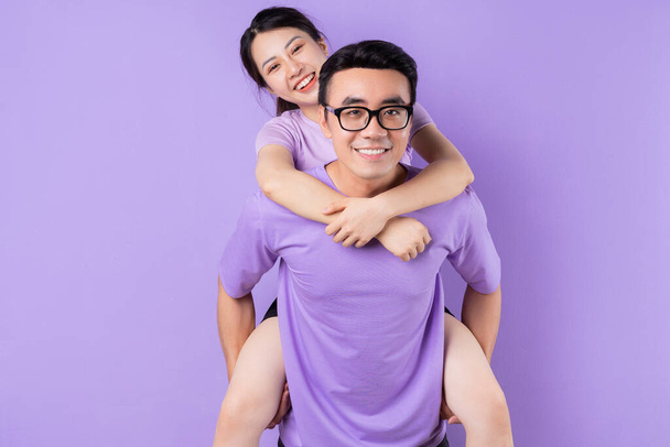 jong aziatisch paar poseren op paars achtergrond - Foto, afbeelding