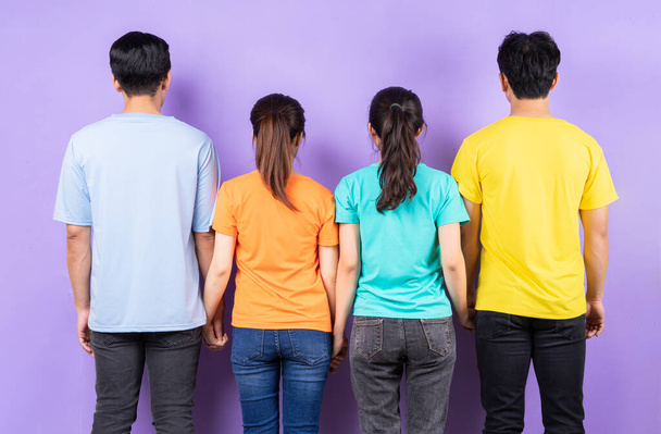 Un grupo de amigos asiáticos cercanos de pie con la espalda sobre un fondo púrpura - Foto, imagen