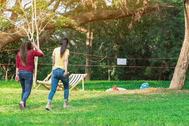 Zadní pohled na asijskou ženu s přáteli procházející společně na trávníku přes zelenou zahradu.Žena relaxační v parku. Šťastní přátelé spolu tráví čas venku v zelené přírodě. Užívám si přírody venku. - Fotografie, Obrázek