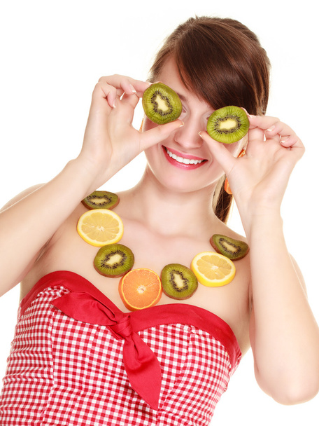Girl in fruit necklace covering eyes with kiwi - Foto, imagen
