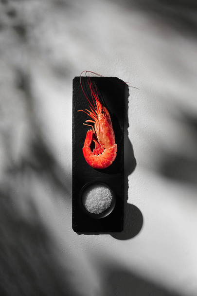 Une crevette cuite sur une planche d'ardoise avec du gros sel de mer - Photo, image