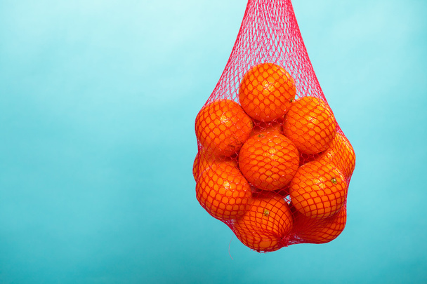 Fresh oranges fruits in mesh from supermarket - 写真・画像