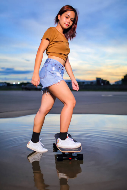 Mulheres asiáticas jogando surf skate ou skates ao ar livre no belo dia de verão. Esporte conceito de estilo de vida atividade, Saudável e exercício. - Foto, Imagem