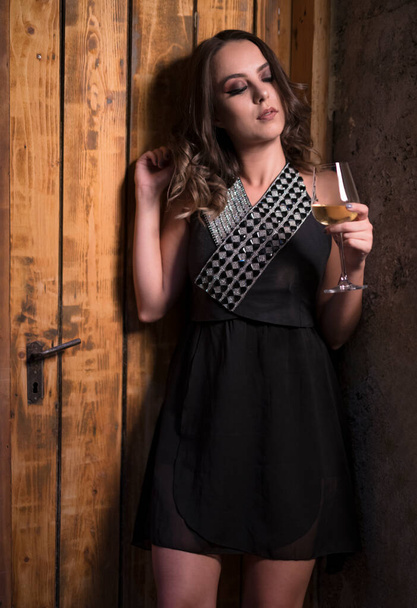beautiful young woman in a black dress and a white shirt on a wooden background - Foto, Imagen