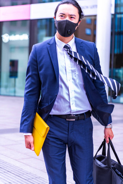 hombre de negocios con traje y máscara caminando por la ciudad - Foto, Imagen
