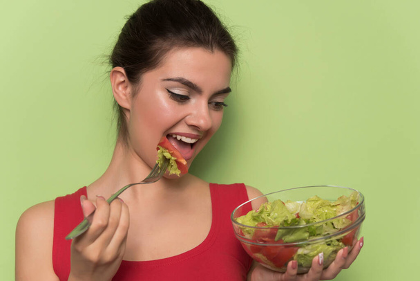 jeune belle femme manger salade saine avec fond vert - Photo, image