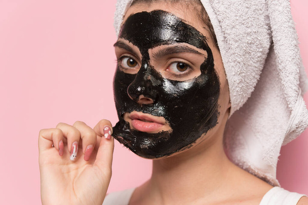 молода жінка з рушником на обличчі наносить маску для обличчя на голову
 - Фото, зображення