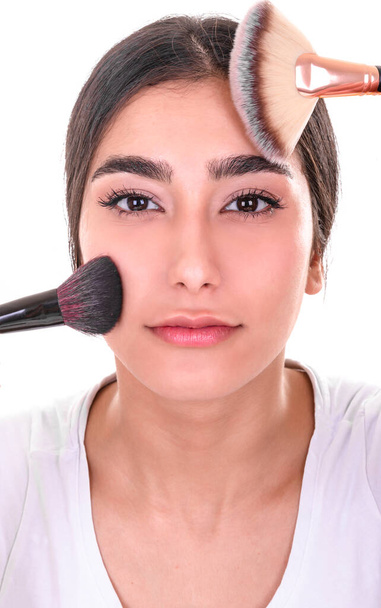 Mooie jonge vrouw met make-up borstel op witte achtergrond - Foto, afbeelding