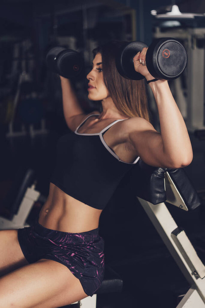 jeune femme avec haltères dans la salle de gym - Photo, image