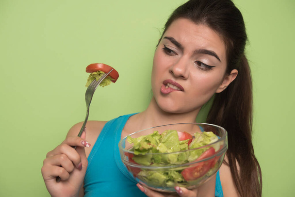 jonge vrouw eet salade met groenten - Foto, afbeelding