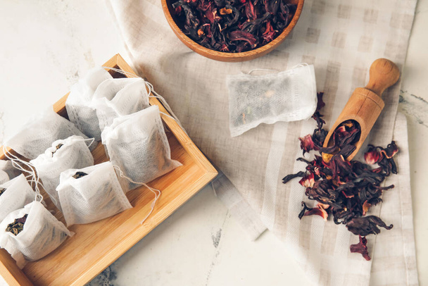 Boîte de sachets de thé avec feuilles sèches sur fond clair - Photo, image