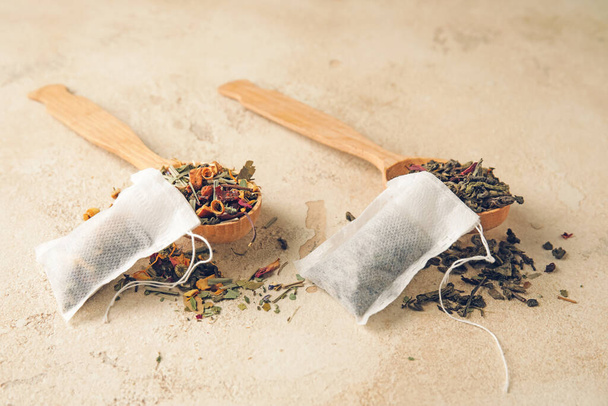 Sacchetti di tè e cucchiai con foglie secche su sfondo chiaro - Foto, immagini