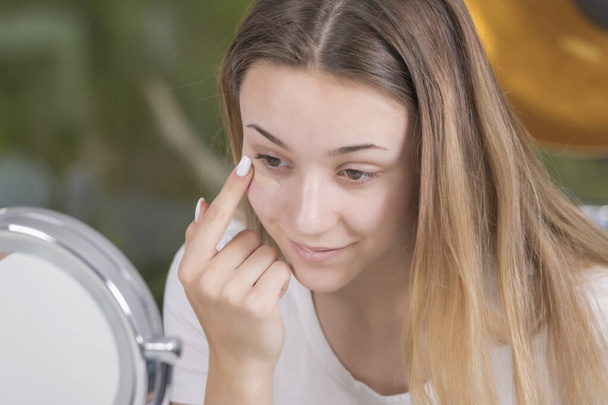 young woman applying makeup on her face - Foto, afbeelding