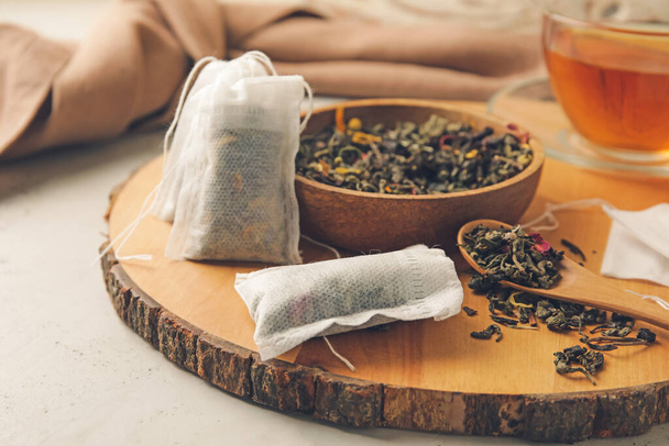 Bolsas de té y tazón con hojas secas sobre fondo claro - Foto, imagen