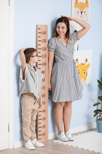 Küçük çocuk ve annesi evde boylarını ölçüyorlar. - Fotoğraf, Görsel
