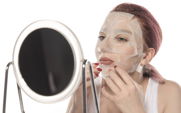 młoda kobieta stosująca maskę kosmetyczną na białym tle - Zdjęcie, obraz