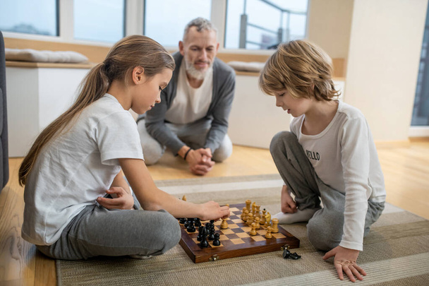 Siblings playing chess while their father watching - Foto, Imagen