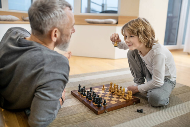 Father and son playing chess and looking involved - Foto, immagini