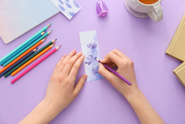 Woman coloring bookmark on color background - Fotó, kép