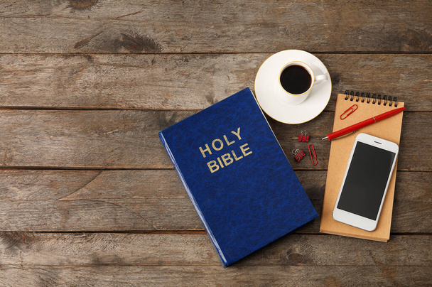 Szent Biblia, csésze kávé, mobil telefon és notebook fából készült háttér - Fotó, kép