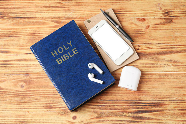木製の背景に聖書、携帯電話やイヤフォン - 写真・画像