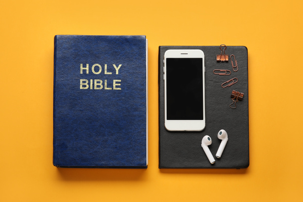 Священна Біблія, мобільний телефон та навушники на кольоровому фоні
 - Фото, зображення