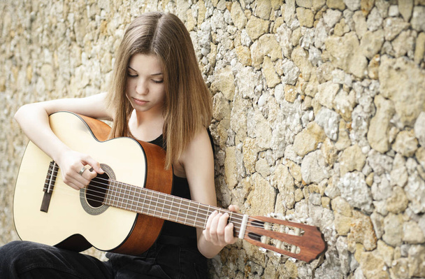 Teini tyttö kitara vastaan ruskea seinä - Valokuva, kuva