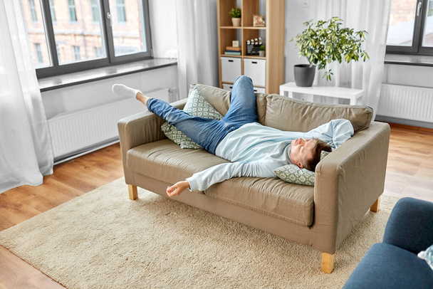 young man sleeping on sofa at home - Фото, изображение