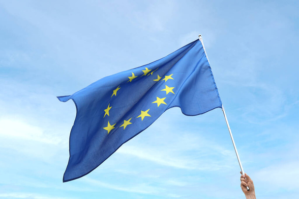Hand with waving flag of European Union on light background - Photo, Image