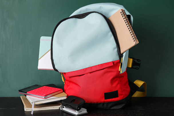 School backpack and stationery near blackboard - Foto, Bild