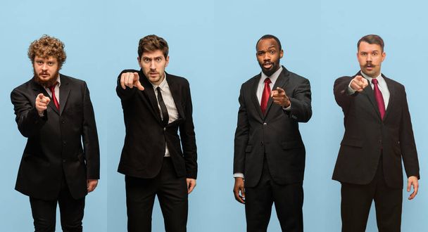 Δείχνοντας, επιλέγοντας. Κολάζ πορτραίτων τεσσάρων ανδρών με σκούρα κοστούμια που απομονώθηκαν σε γαλάζιο φόντο στούντιο. - Φωτογραφία, εικόνα