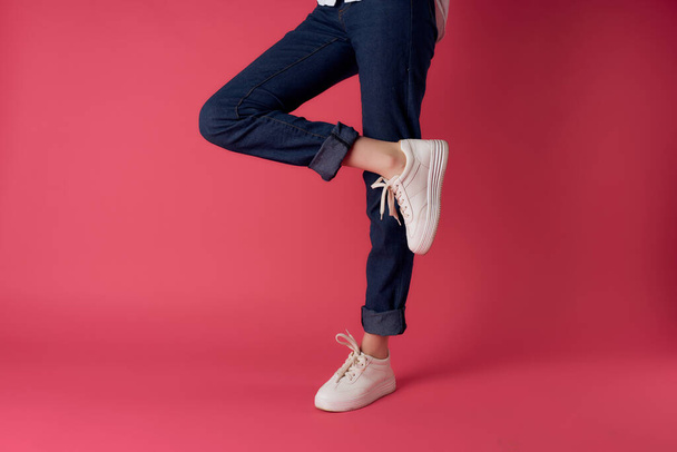 ピンクの背景をしたファッションの白いスニーカーの女性の足 - 写真・画像