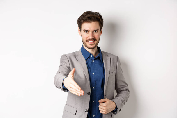Empresário confiante esticar a mão para o aperto de mão de negócios e sorrindo, apresentar-se na reunião, de pé sobre fundo branco - Foto, Imagem