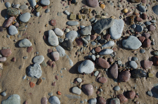 Détail d'une plage de sable mouillé avec des galets lisses
 - Photo, image