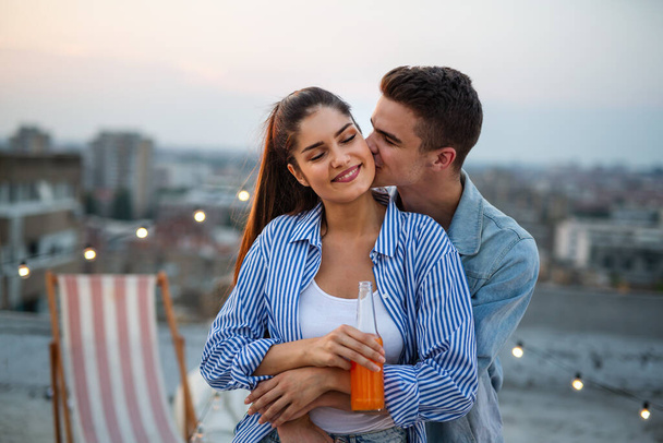 Young happy couple in love having fun at rooftop party in sunset. - Foto, Imagem