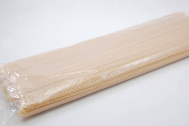 Сырые длинные палочки спагетти макароны в пластиковой упаковке - Фото, изображение