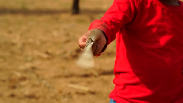 Neşeli Hintli çocuk elinde kırmızı tişörtle yel değirmeni oyuncağı taşıyor. Çocukluk kavramı. - Video, Çekim