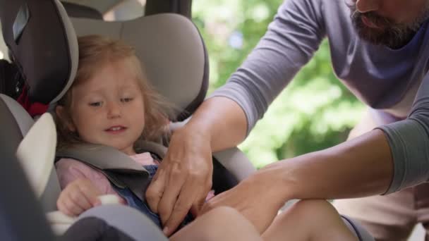 赤ちゃんの車の座席に娘を確保する父親のビデオ。8Kでレッドヘリウムカメラで撮影. - 映像、動画