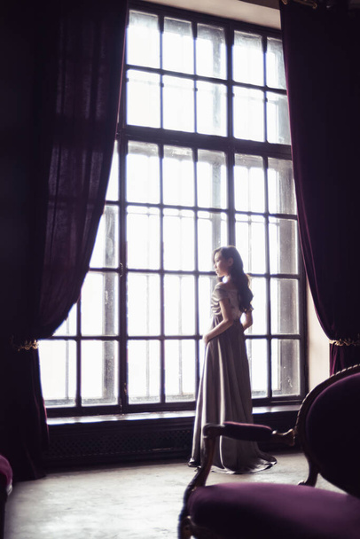 Pencerenin yanında güzel elbiseli, hamile bir Asyalı kadın var. - Fotoğraf, Görsel
