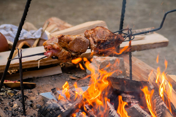 Prozess des Kochens von großen Fleischstücken am Spieß über offenem Feuer - Foto, Bild