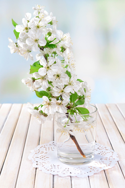 Beautiful fruit blossom in glass on table on light background - Fotó, kép