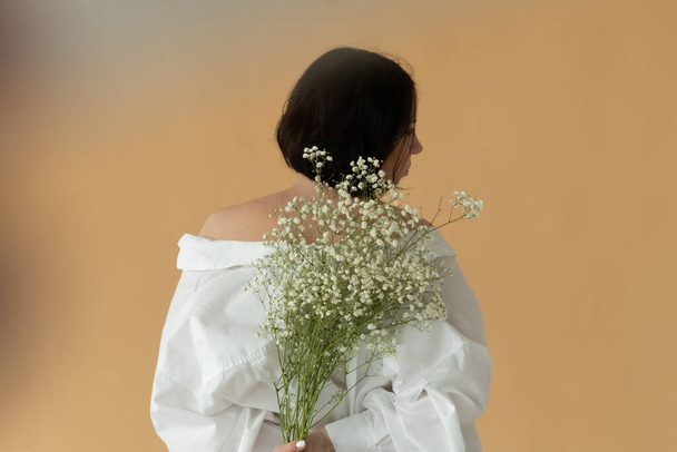 jovem bela mulher posar com flores brancas no estúdio - Foto, Imagem
