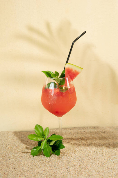 tropický studený meloun nápoj se zelenými tropickými listy na písčitém béžovém pozadí.letní slunné stíny koncept - Fotografie, Obrázek