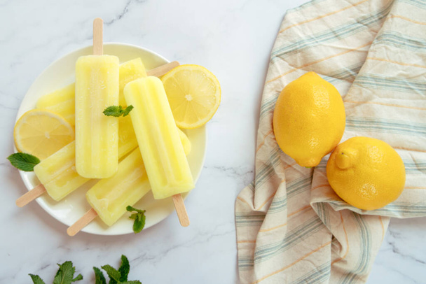 citroen pops op een plat linnen ijs met verse citroenen op de achtergrond - Foto, afbeelding