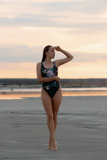 Sensual joven hembra disfrutando de la puesta de sol en la costa arenosa - Foto, imagen