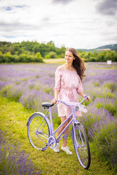 Frau in rosa Kleid mit Retro-Fahrrad im Lavendelfeld, Tschechien - Foto, Bild