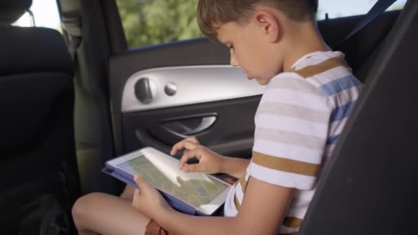 Портативное видео мальчика с планшетом во время поездки по дороге. Съемка с красной гелиевой камерой в 8K. - Кадры, видео