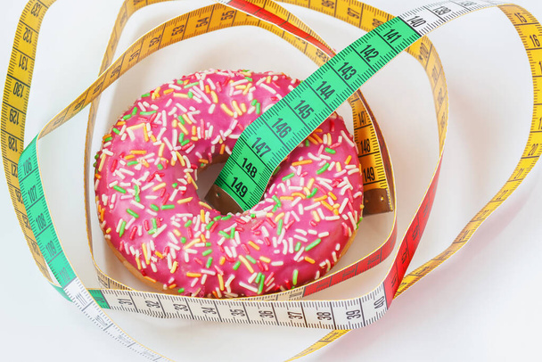 Glazed donut and tape measure close-up. Concept of healthy food, diet, overweight - Foto, Imagem