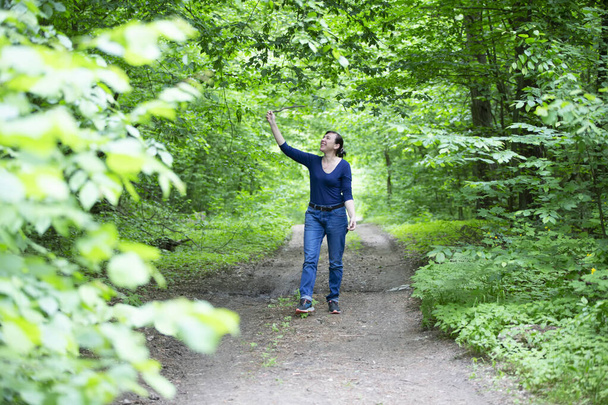 Boldog középkorú nő sétál a nyári erdőben. - Fotó, kép
