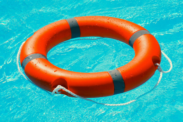 Levensring drijvend op zonnig blauw water. Reddingsring in zwembad - Foto, afbeelding